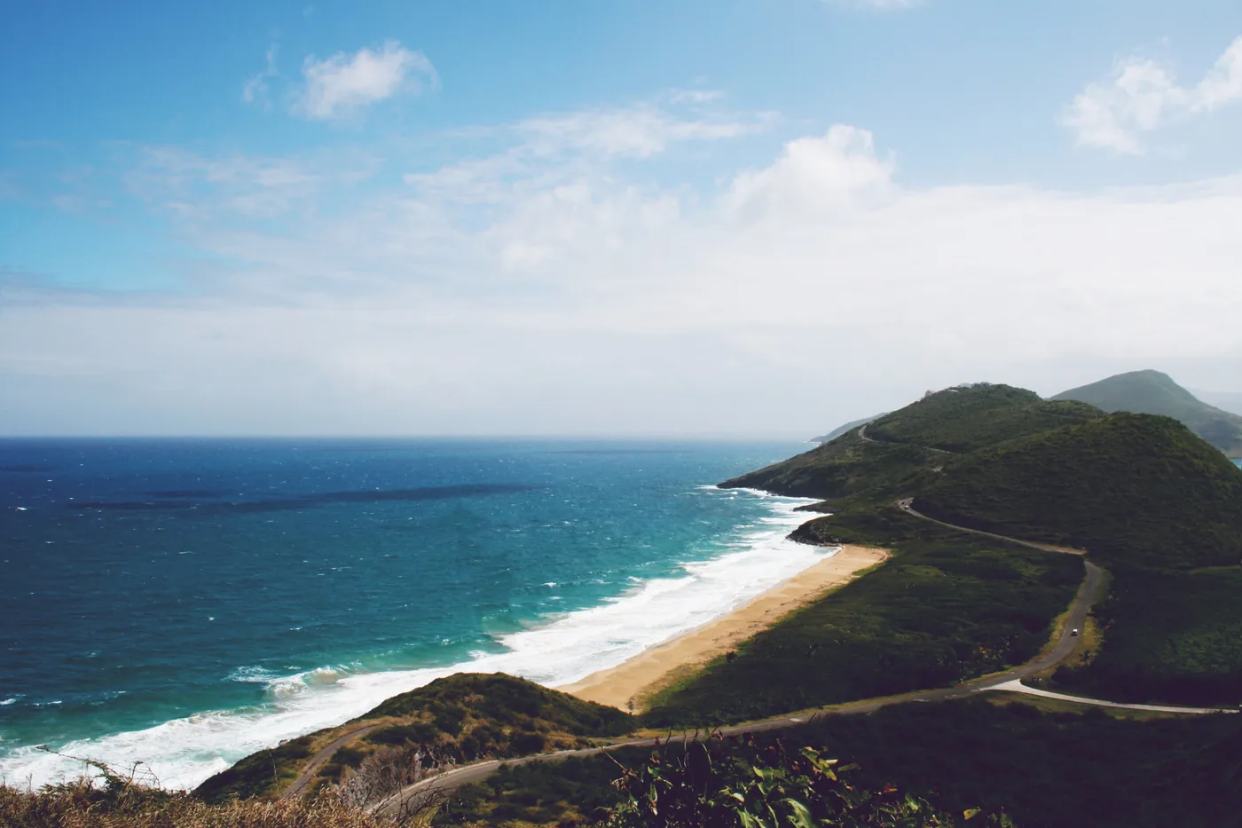 Ein Strand und eine grüne Landzunge an der Küste von St. Kitts